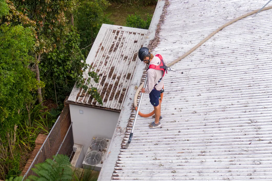 kg-gutter-cleaning-1 Aerial top-down view of Kleen Genie technician using gutter cleaning equipment on corrugated roof