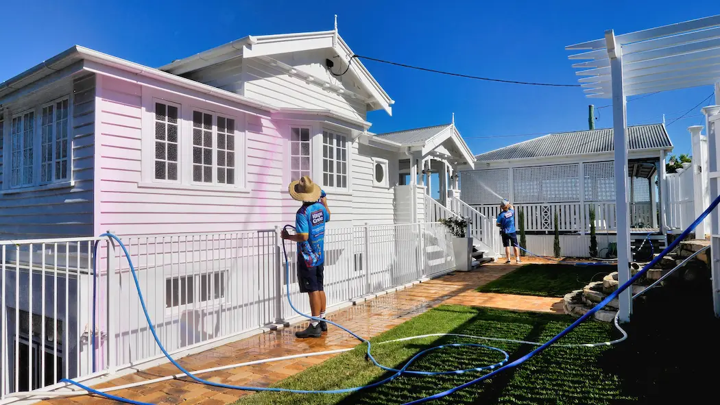 Kleen Genie technician spraying chemicals on exterior house facade