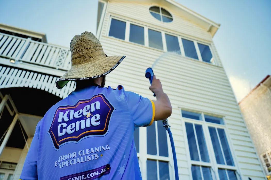 Kleen Genie technician washing exterior house facade with water jet