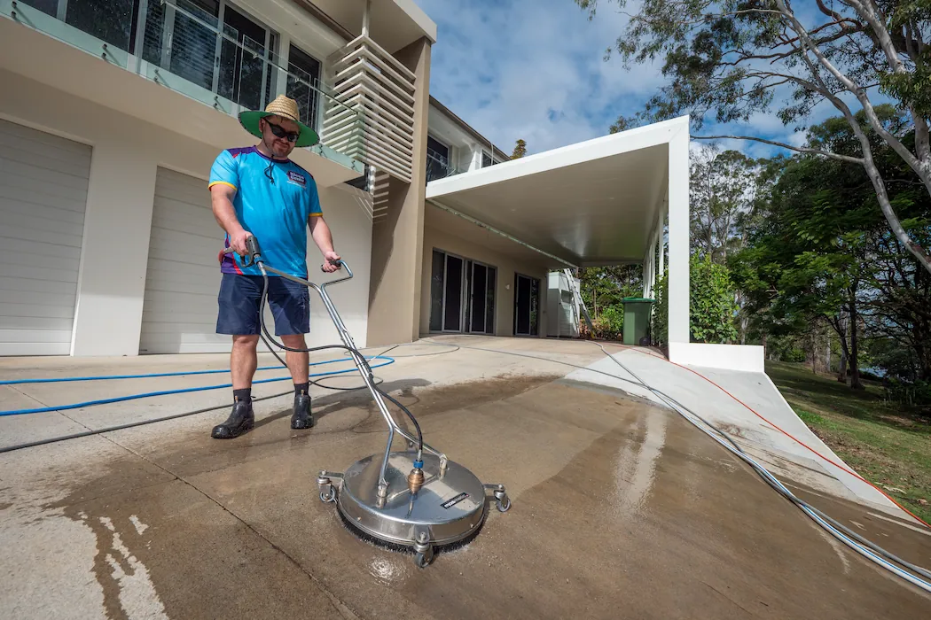 kg-pressure-washing-2 Kleen Genie technician using high-powered pressure cleaning equipment on a driveway